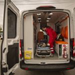 An EMT loads a person on a stretcher into an ambulance.